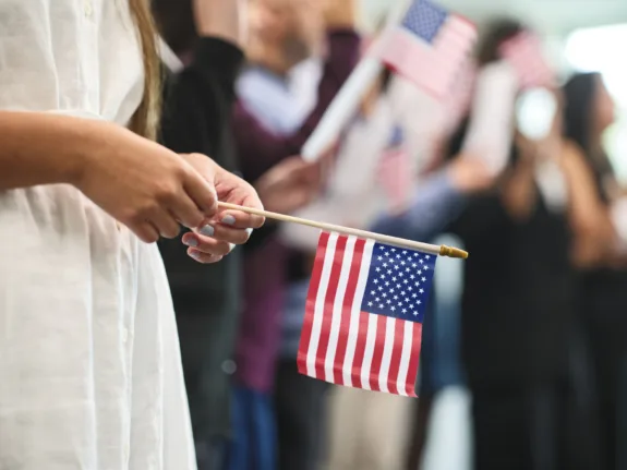 A diverse group of people in a ceremony taking the United States Naturalization Oath of Allegiance to become citizens.
